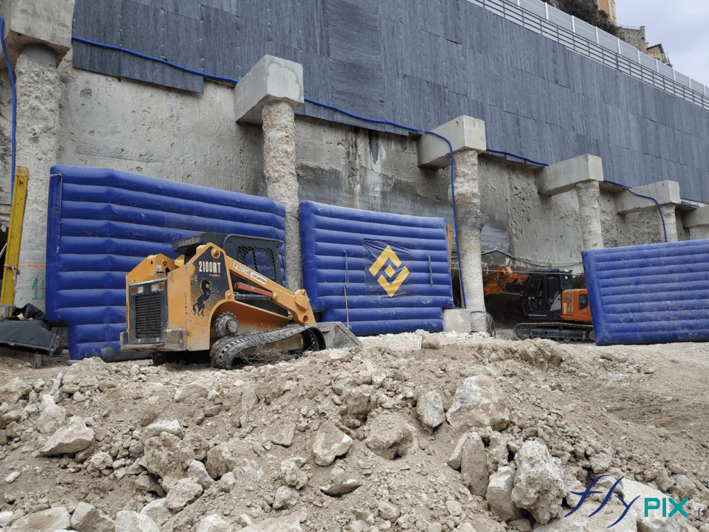 Plusieurs segments de murs gonflables de réduction de bruits (anti-acoustiques), disposés à plusieurs endroits du chantier en ville.