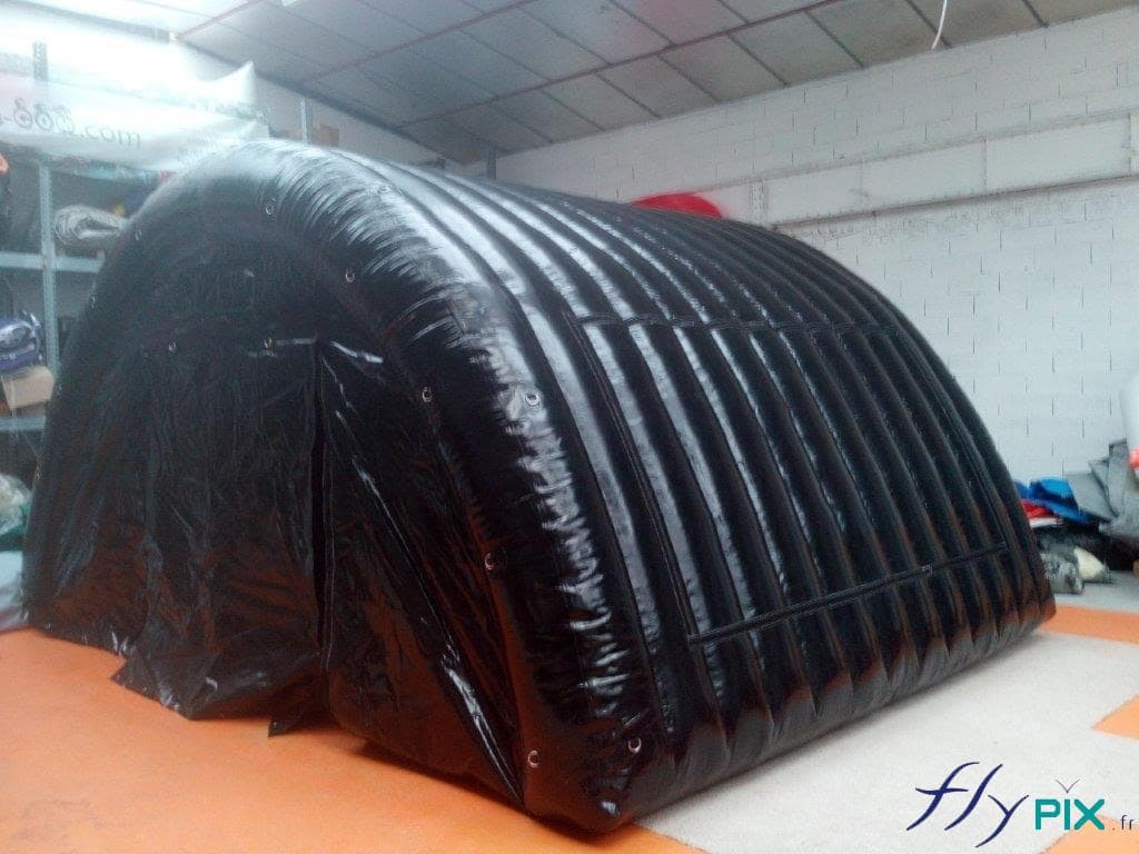 Une tente gonflable tunnel de stockage de matériel, en forme de demi-lune, et avec une enveloppe PVC 0.6 mm double peau de couleur noire.