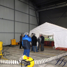 Une tente industrielle air ventilée utilisée en environnement intérieur pour le nettoyage de grosses pièces de machines industrielles.