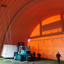 Un véhicule monte-charge opère avec un container à l&#039;intérieur d&#039;un hangar gonflable industriel.