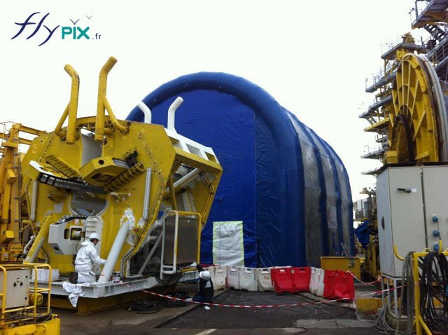 Un hangar gonflable en forme de U inversé, la machine jaune devant la porte devra être nettoyée à l'intérieur.