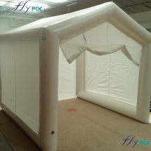 Tente gonflable en forme de maison, avec des grandes ouvertures, pour des chantiers de menuiserie, pour la pose de portail, en extérieur.