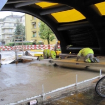 Tente de chantier gonflable: des ouvriers travaillent la pose de béton au sol, en étant protégé de la pluie et des intempéries.