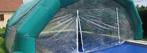 Tente gonflable abri piscine à 5 pans coupés, couvrant une partie de la piscine.