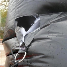 Un anneau de fixation métallique a été arraché au niveau d'un boudin d'ossature d'une tente gonflable.