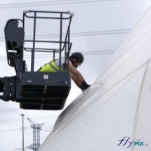 Utilisation d'un monte charge pour la réparation d'une toiture d'un hangar gonflable, en environnement extérieur.