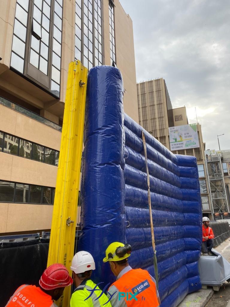 Des techniciens das un chantier urbain sont entrain d'installer un mur de réduction de bruit gonflable.