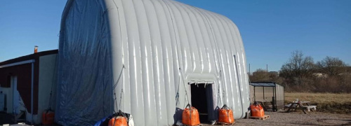Disposition du hangar  gonflable en forme de U inversé, fixé par les haubans, aux sacs de lestages remplis de sables. Vous pouvez voir la porte d'accès latérale. Les murs en enveloppe PVC 0.6 mm double peau capitonnée est très robuste et très solide.