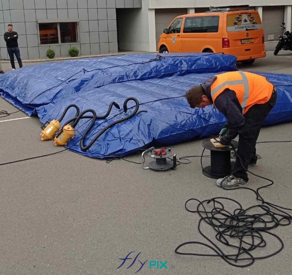 Un technicien est entrain de gonfler un mur gonflable de réduction de bruits avec une pompe électrique.