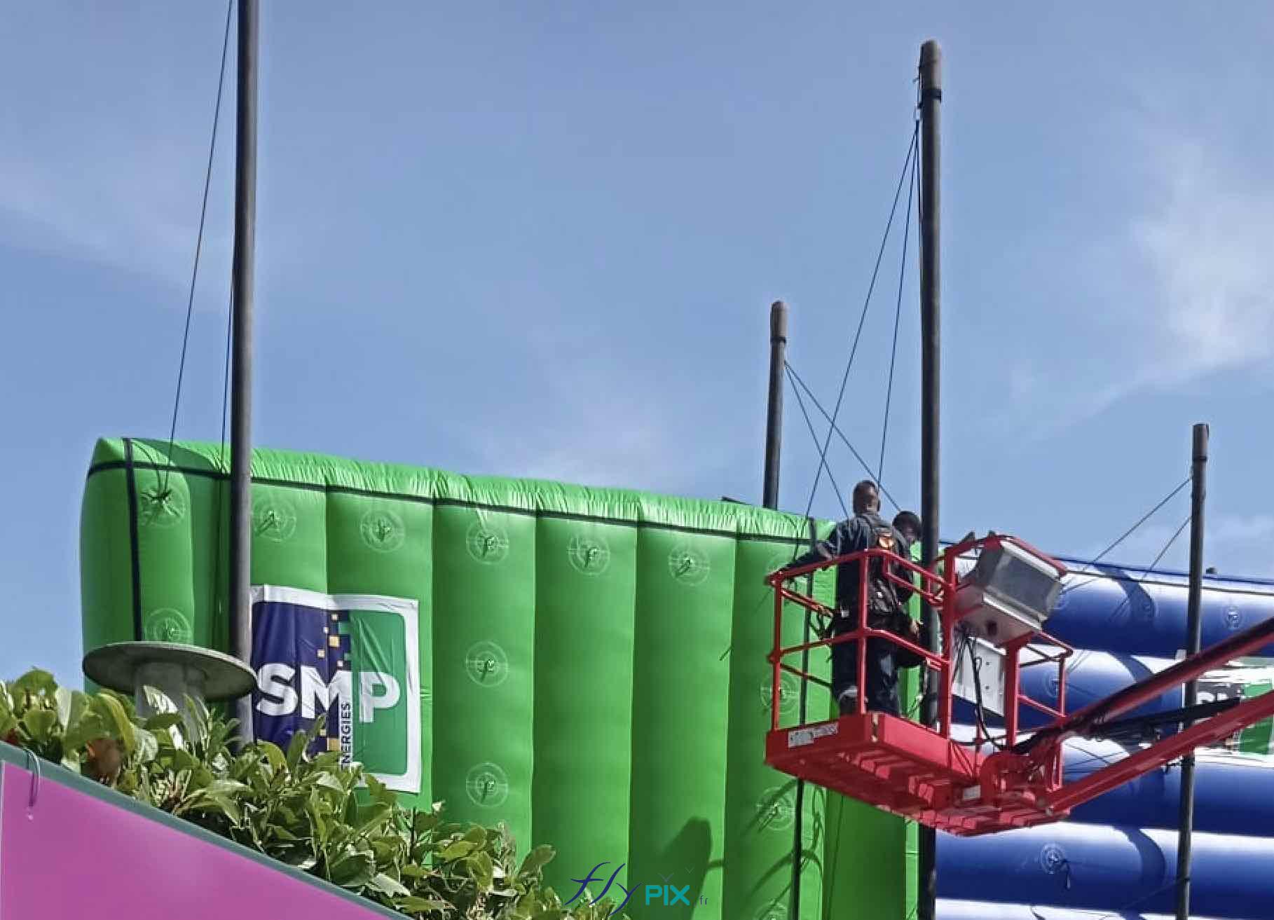 Des techniciens au sommet d'une nacelle sont entrain de manœuvrer pour faire l'installation des murs gonflables de réduction de bruits sur le chantier de SMP Drilling / SMP Energies.