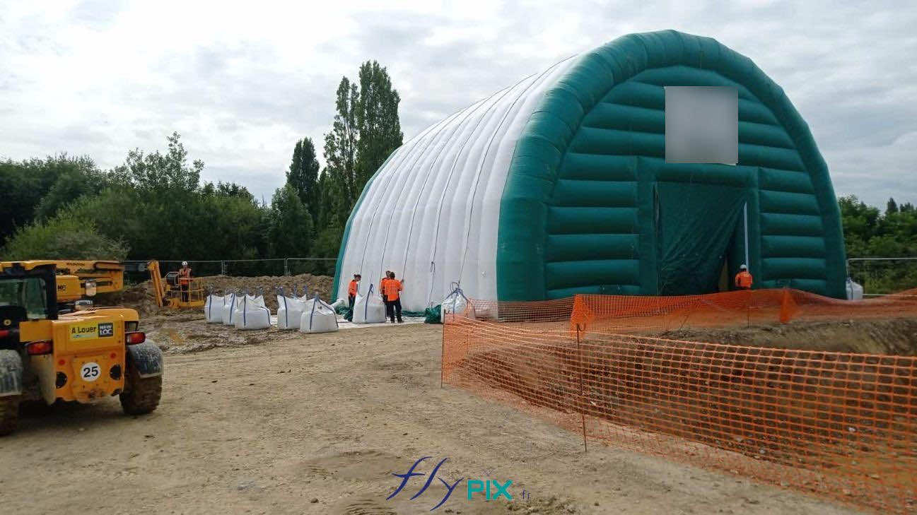 , Chantier de dépollution de site : 2 modules de hangar gonflable de S = 200 m2, soit S = 400 m2 de surface utile de travail,  Une très belle photo d’ensemble du chantier et de la tente gonflable, présentant la configuration du terrain et la disposition de l’abri gonflable une fois installé par les techniciens. C’est une très belle réalisation qui répond un un besoin spécifique très utile : dépolluer les sols en zone confinée et à atmosphère contrôlée. Cette preuve de concept démontre la faisabilité de la mise en oeuvre et de l’utilisation d’abris gonflables de grandes surfaces et dimensions pour différents besoins de chantiers (BTP, rénovation, dépollution, nettoyage, aéronautique, industrie…). Nous avons l’expérience et le savoir faire pour concevoir et fabriquer des tentes gonflables sur mesure adaptés à vos besoins en modularité, polyvalence et en ergonomie. – Photo : copyright FlyPix/Vivien LAÏLLE, droits réservés.