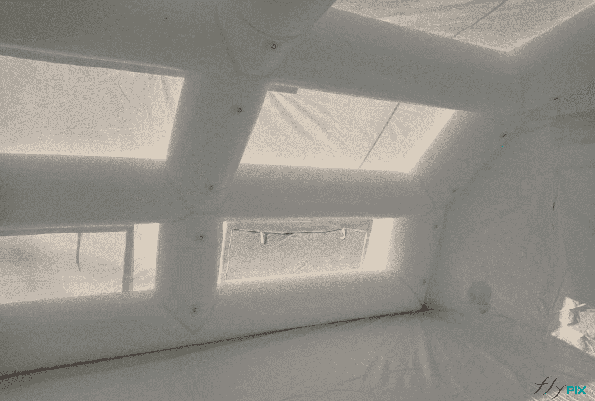 Une vue intérieure de la tente gonflable PMA (Posté Médical Avancé), avec la bâche au sol, les boudins d'ossatures, les anneaux et œillets de fixations internes, des fenêtres avec volets et moustiquaires. L'enveloppe et les fenêtres permettent de disposer d'un éclairage naturel et diffus pour les diagnostics médicaux des patients. Nous avons prévu des anneaux et des œillets de fixations métalliques, qui permettent de fixer des éclairages LED, ce qui signifie que le personnel soignant et les médecins peuvent soigner ou opérer de jour comme de nuit. - Copyrights Vivien LAÏLLE / FlyPix - Droits réservés, reproductions interdites.