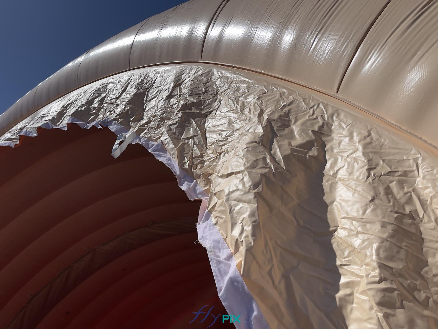 , Hangar gonflable militaire L = 25 m x l = 14 m x H = 7 m, S = 350 m2,  Chaque module du hangar gonflable militaire sont doté d'une interface composée d'une bâche qui permet l'assemblage entre 2 modules, et d'assurer l'étenchéité grâce à un raccord par l'intérieur. Sur cette photo, nous voyons le raccord et aussi les attaches qui assurent la jointure et la jonction de 2 modules gonflables. - Copyright : Vivien LAÏLLE/FLYPIX, droits réservés.
