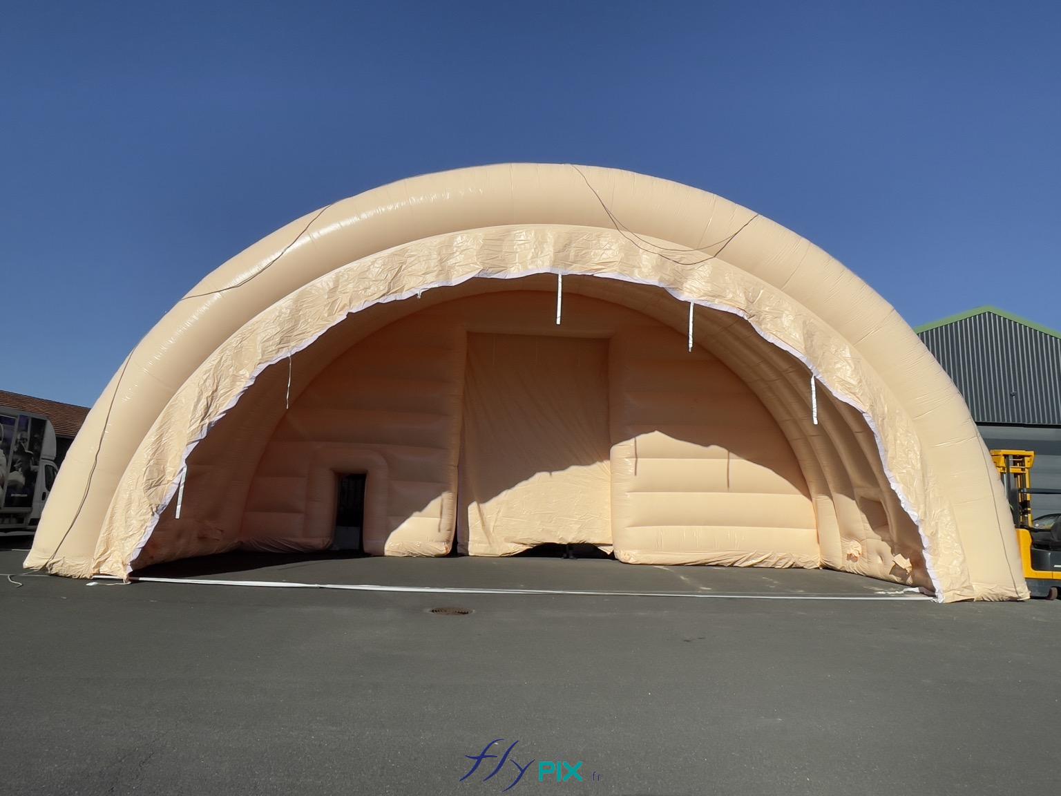, Hangar gonflable militaire L = 25 m x l = 14 m x H = 7 m, S = 350 m2,  Une vue générale prise depuis le sol, qui montre un module de tente gonflable en forme de tunnel demi-lune. Cette forme est très stable et très robuste, parce que elle procure des des bons contreforts naturels, avec une clef de voute, et des murs qui répartissent efficaement les charges de la structure gonfable vers le sol. Exactement comme les catédrales. - Copyright : Vivien LAÏLLE/FLYPIX, droits réservés.