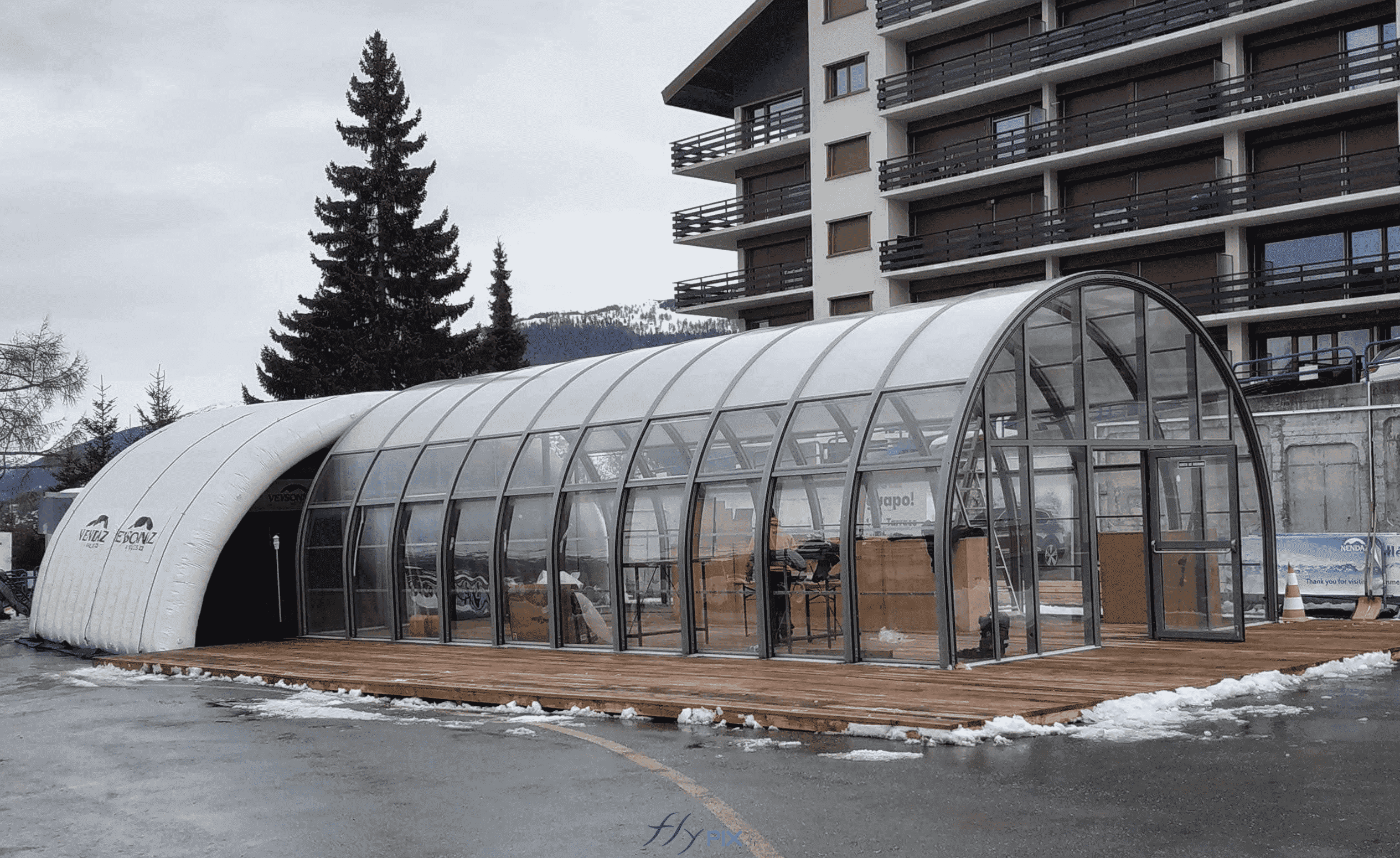 Sur cette photo, nous voyons une structure en verre et avec des armatures métalliques, en forme de tunnel demi-lune, au premier plan, destinée à accueillir des visiteurs et du public. Au fond, l'arrière-plan, nous pouvons observer la tente gonflable en forme de tunnel demi-lune, une structure gonflable air captif, en enveloppe PVC 0.6 mm double peau capitonnée. Elle est gonflée à l'air avec une pompe électrique et un régulateur de pression. Le module est une extension permettant de disposer d'une surface utile plus spacieuse pour accueillir une scène de spectacle. Sur cette photo, nous voyons une structure en verre et avec des armatures métalliques, en forme de tunnel demi-lune, au premier plan, destinée à accueillir des visiteurs et du public. Au fond, l'arrière-plan, nous pouvons observer la tente gonflable en forme de tunnel demi-lune, une structure gonflable air captif, en enveloppe PVC 0.6 mm double peau capitonnée. Elle est gonflée à l'air avec une pompe électrique et un régulateur de pression. Le module est une extension permettant de disposer d'une surface utile plus spacieuse pour accueillir une scène de spectacle.