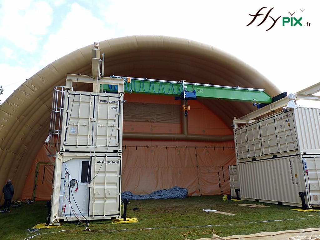 NEXTER : un module de hangar gonflable militaire de grande taille, avec une structure de grue et de containers pour la manoeuvre, placés à l'intérieur de l'abri gonflable.