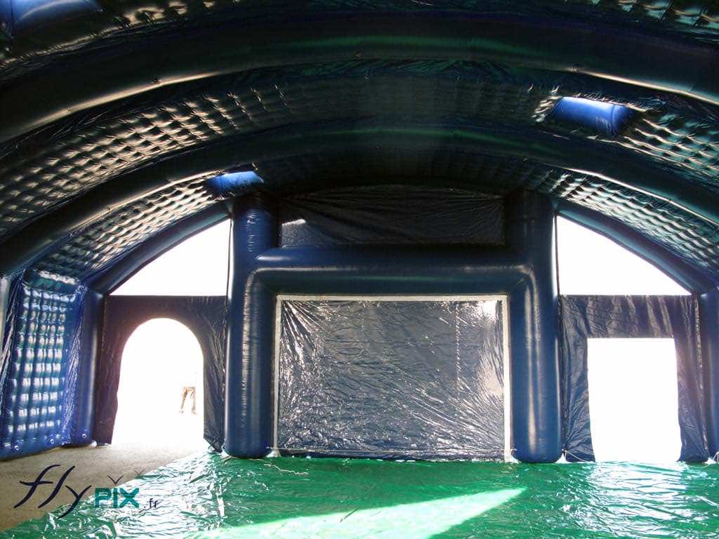 IUT de NANTES : une vue intérieure du hangar gonflable, prise de l'autre coté du pignon de la façade avant, avec à gauche et à droite 2 portes d'accès et au centre une grande fenêtre amovible transparente avec volet amovible. Une bâche au sol est en cours de déploiement, sur lequel il y aura un sol technique adapté.