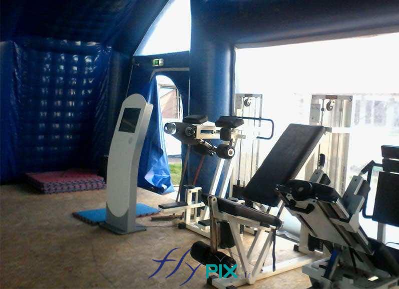 IUT de NANTES : une vue intérieure du grand hangar gonflable, une salle de sport mobile et temporaire, avec différentes machines de sport installés sur un sol technique. Des grandes fenêtre de points de jour permettent aux sportifs de bénéficier d'une ambiance de lumière naturelle.