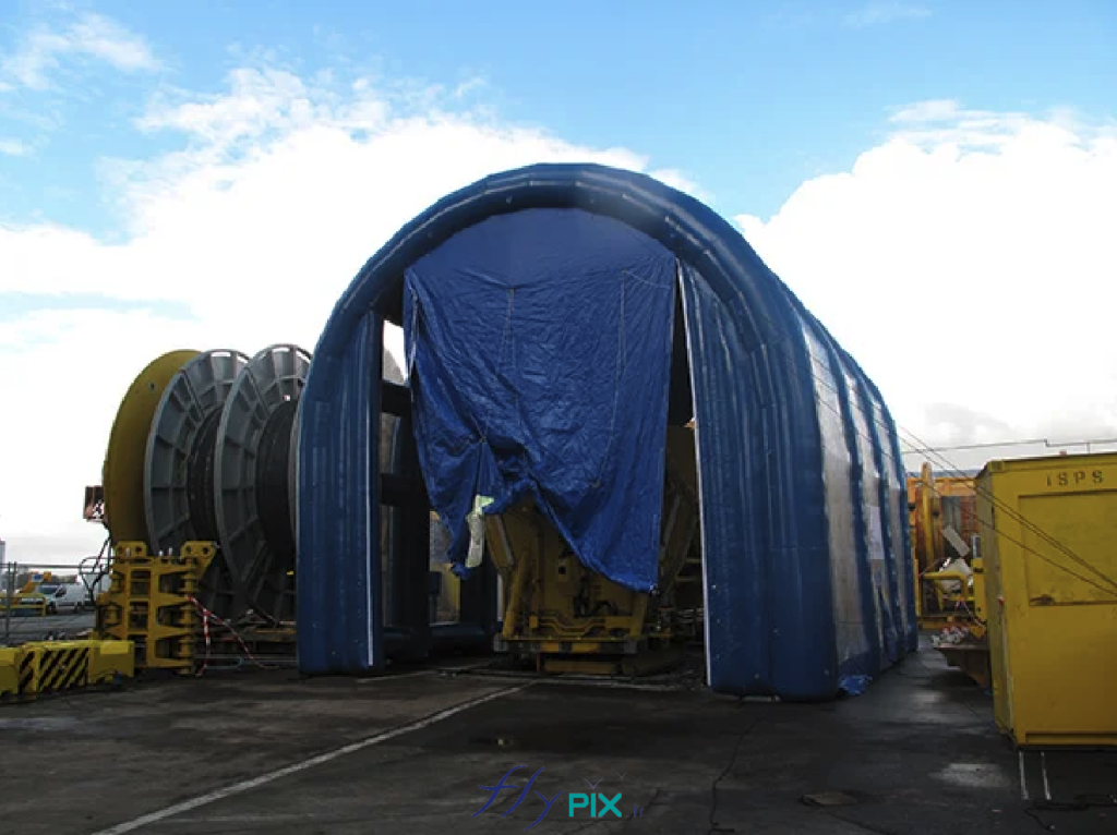 Une vue générale extérieure d'un grand hangar gonflable U-inversé, avec une grande porte large pignon. Cette structure gonflable a été fabriquée sur mesure par nos soins, dans nos ateliers, en France à Orléans.