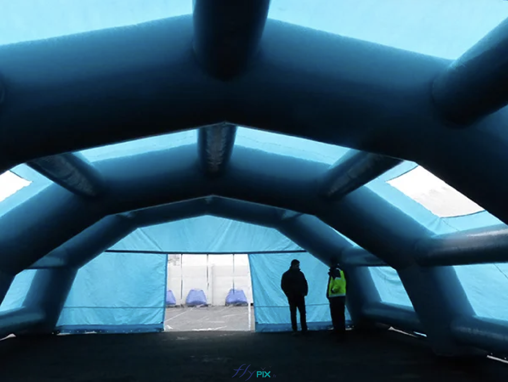 Une vue intérieure d'une tente gonflable en forme de tunnel demi-lune, avec les boudins d'ossatures qui sont le squelette de la structure gonflable. Cet abri gonflable de chantier est entièrement en enveloppe PVC 0.45 mm simple peau. Il a été fabriqué sur mesure par nos soins dans nos ateliers à Orléans, en France. Une vue intérieure d'une tente gonflable en forme de tunnel demi-lune, avec les boudins d'ossatures qui sont le squelette de la structure gonflable. Cet abri gonflable de chantier est entièrement en enveloppe PVC 0.45 mm simple peau. Il a été fabriqué sur mesure par nos soins dans nos ateliers à Orléans, en France.