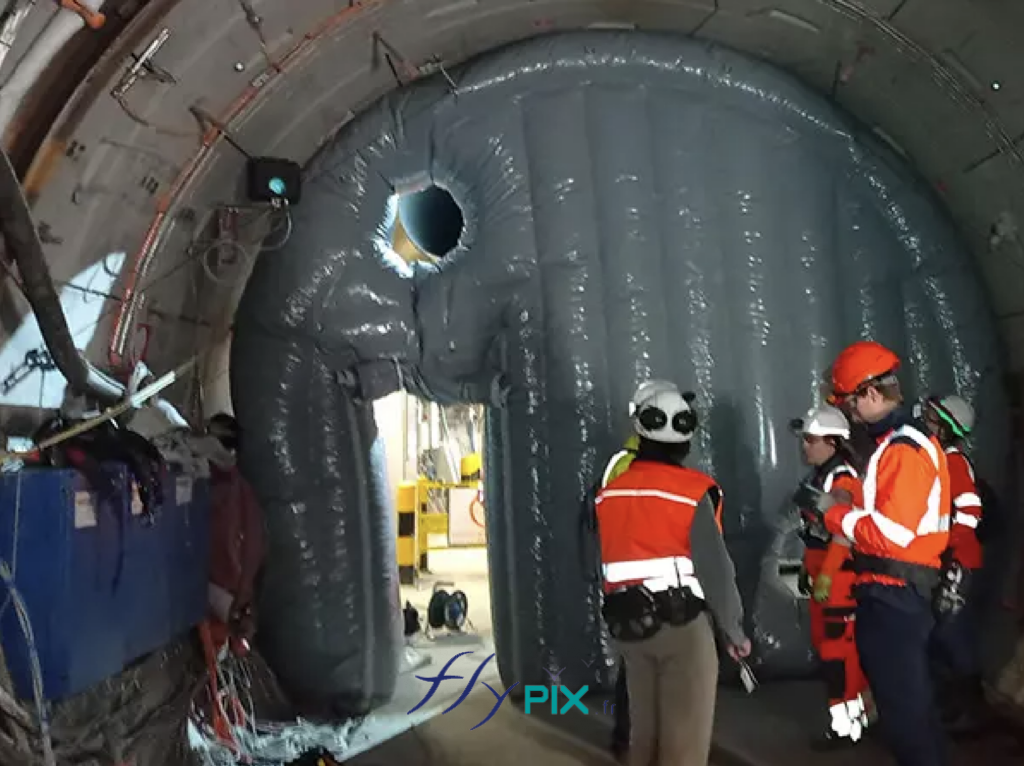 Cette structure gonflable sert à compartimenter le laboratoire souterrain afin d'empêcher les poussières et les particules de se propager vers le reste des infrastructures. Ce dispositif gonflable permet de sectoriser le laboratoire souterrain afin de bloquer la dispersion de poussières et de particules. Grâce à sa conception modulable, il s'installe et se retire aisément, offrant un déploiement rapide selon les besoins des essais (sécurité, étanchéité ou confinement). Les expérimentations menées valident ainsi ses futures applications, notamment le contrôle des sédiments, la résistance des matériaux et la performance des barrières d'isolation. – Droits réservés, reproduction interdite. Copyright FlyPix / Vivien LAÏLLE.