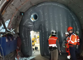 Cette structure gonflable sert à compartimenter le laboratoire souterrain afin d'empêcher les poussières et les particules de se propager vers le reste des infrastructures. Ce dispositif gonflable permet de sectoriser le laboratoire souterrain afin de bloquer la dispersion de poussières et de particules. Grâce à sa conception modulable, il s'installe et se retire aisément, offrant un déploiement rapide selon les besoins des essais (sécurité, étanchéité ou confinement). Les expérimentations menées valident ainsi ses futures applications, notamment le contrôle des sédiments, la résistance des matériaux et la performance des barrières d'isolation. – Droits réservés, reproduction interdite. Copyright FlyPix / Vivien LAÏLLE.