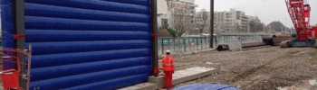 Grand Paris Express, chantier urbain de Meudon : cette photo est intéressante parce qu'elle montre plusieurs choses essentielles qui concerne les structures gonflable de murs de réduction de bruits. Premièrement, au premier plan, au sol, un écran gon flable est déployé sur toute sa surface, dans l'attente de son gonflage à l'air avec une pompe électrique. C'est une structure air captif. Deuxièmement, en arrière plan, nous observons un mur gonflé, positionné verticalement sur une structure en béton et avec des poutres métalliques. Cette configuration procure une très grande résistance structurelle aux vents, tout en minimisant au maximum l'emprise au sol, en limitant la présence et l'utilisation de sacs de lestages à remplir de sable. Tout en conservant une grande mobilité et un très bon réemploi.